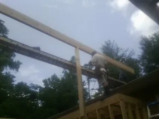 Carpenter setting a ridge beam over a new addition frame — Ice Dam Removal by Roofing Brothers in Massey
