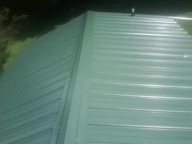 New green metal panels meeting at the ridge of a roof — Flat Roof Repair work by our crew in Massey