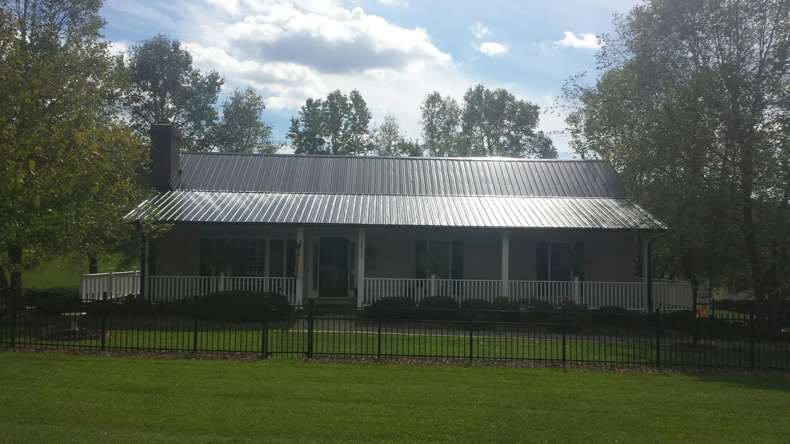 Gray metal roof on a brick ranch with a full width front porch — Gutter Guard Installation work by our crew in Massey